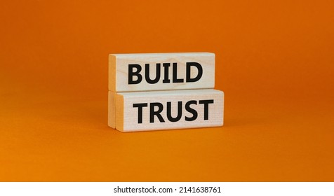 Build trust symbol. Concept words Build trust on wooden blocks on a beautiful orange table orange background. Business and build trust concept, copy space.