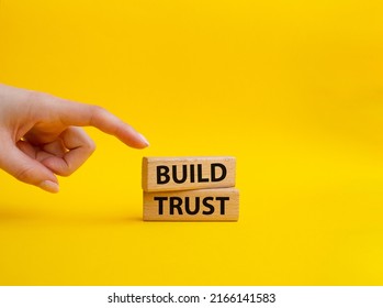 Build trust symbol. Wooden blocks with words Build trust. Beautiful yellow background. Businessman hand. Business and Build trust concept. Copy space.