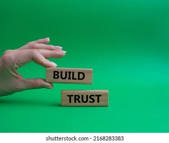Build trust symbol. Wooden blocks with words Build trust. Beautiful green background. Businessman hand. Business and Build trust concept. Copy space.
