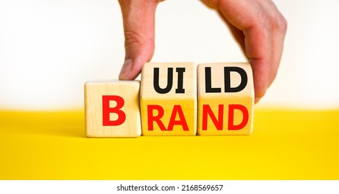 Build your brand symbol. Concept words Build brand on wooden cubes. Businessman hand. Beautiful yellow table white background. Build your brand and business concept. Copy space.