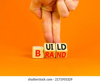 Build your brand symbol. Concept words Build brand on wooden cubes. Businessman hand. Beautiful orange table orange background. Build your brand and business concept. Copy space.