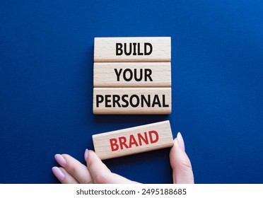 Build your personal Brand symbol. Concept words Build your personal Brand on wooden blocks. Businessman hand. Beautiful deep blue background. Business and Build your personal Brand concept. Copy space - Powered by Shutterstock