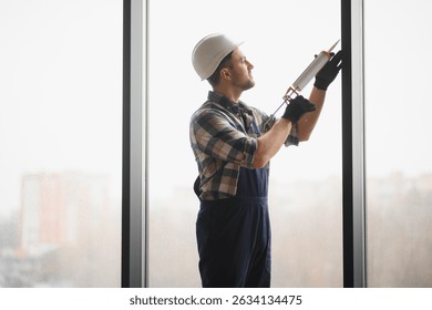 Builder applying sealant during window installation in a newly constructed building, ensuring quality and precision for optimal performance