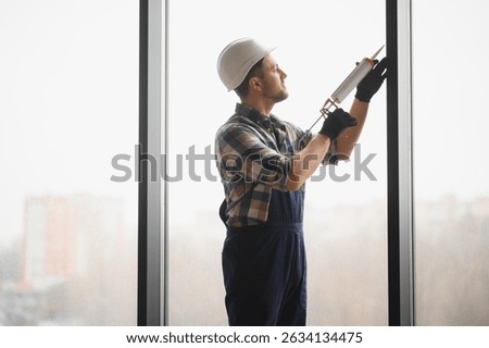 Builder applying sealant during window installation in a newly constructed building, ensuring quality and precision for optimal performance