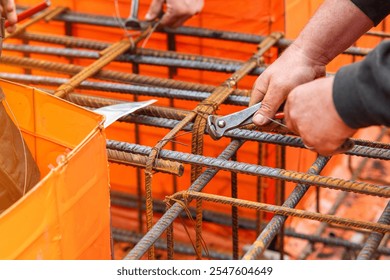Builder assembling steel rebar framework for concrete construction at a building site in afternoon sunlight