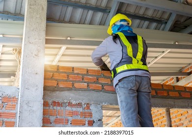 Builder Carefully Puts Red Brick On The Masonry. Quick Work Bricklayer. Guy Measures Level Masonry. Man Is Building Brick Wall. Correctly Calculate Material. Builder Manually Carries Brick Structure,B