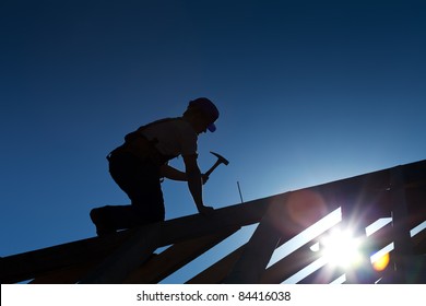 Builder or carpenter working on the roof - silhouette with strong back light