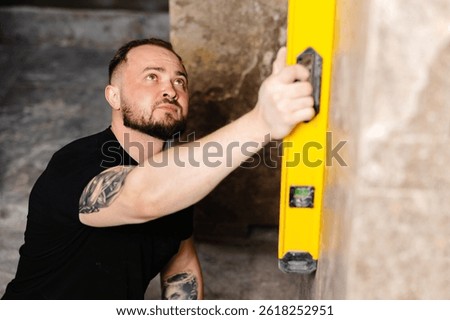 Builder checking the evenness of marble tiles with a level tool, ensuring precision and accuracy during renovation work on a wall