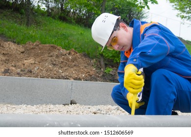 The Builder Checks The Progress Of The Laying Of Curbstone, The Mound Of Rubble And Takes Measurements