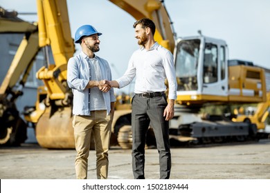 Builder Choosing Heavy Machinery For Construction, Talking With A Sales Consultant On The Open Ground Of A Shop With Special Vehicles