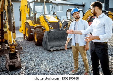 Builder Choosing Heavy Machinery For Construction With A Sales Consultant On The Open Ground Of A Shop With Special Vehicles