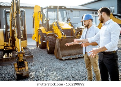 Builder Choosing Heavy Machinery For Construction With A Sales Consultant On The Open Ground Of A Shop With Special Vehicles