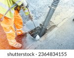 Builder cleaning blocked road gully with shovel and vacuum excavator