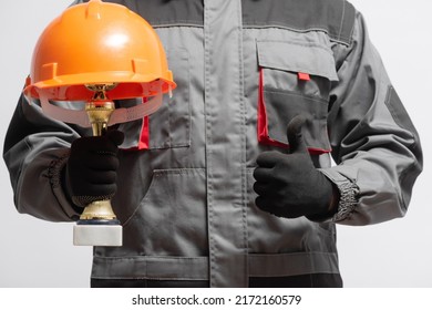 Builder contractor with the golden award trophy cup with the hardhat above is showing a thumbs up gesture close up. Best worker concept. Good job. - Shutterstock ID 2172160579