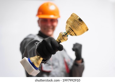Builder contractor in the hardhat with a golden award cup in hand isolated on the white background. Best worker of the year concept.
