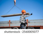 A builder controls a crane while unloading panels to cover a house.