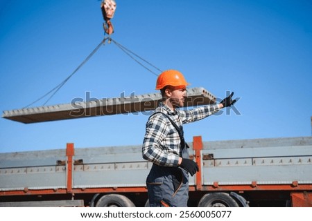 A builder controls a crane while unloading panels to cover a house.