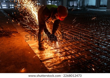 The builder cuts the rebar with an angle grinder. Cutting metal with sparks