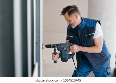 Builder Cutting A Round Hole In Wooden Cladding Indoors In A New Build House With A Power Drill