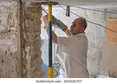 Builder With Demolition Hammer Breaking A House Wall.