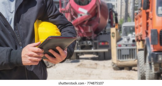 Builder With Digital Tablet Working On A Heavy Construction Site.