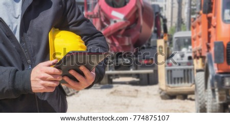 Builder with digital tablet working on a heavy construction site.