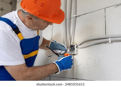 Builder electrician electrical engineer working to connect all the cables according to the project of the electrical installation of a new house