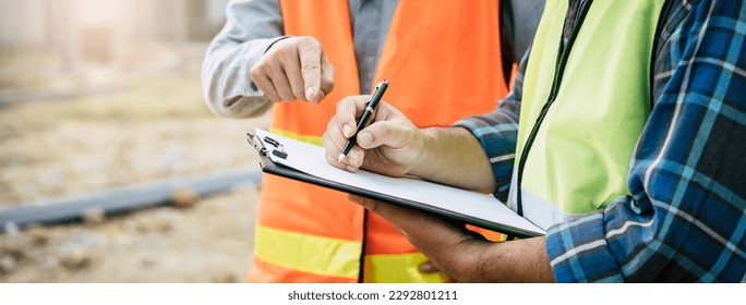 Builder engineer and supervisor consultant inspection job plan  concept, Asian contractor and foreman looking blueprint in computer laptop and checking process plan of factory warehouse construction - Powered by Shutterstock