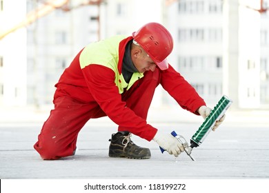 Builder Filling Joint Of Concrete Board With Industrial Polyurethane Sealing Foam In Protective Workwear At Construction Area