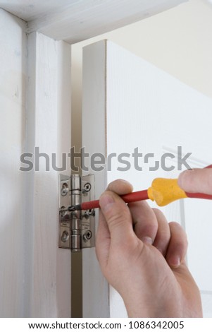 A builder fixing a door to a hinge
