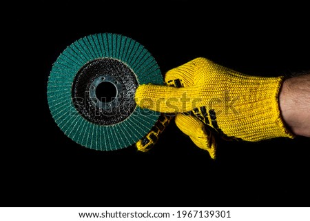 Builder hand in glove keeps or gives abrasive tools close up on isolated black background. The idea of starting a successful work. Free advertising space.