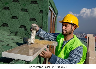 The builder is hitting the marble with a hammer and leveling it with a spirit level. The master replaces a polished marble handrail. - Shutterstock ID 2244023521
