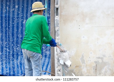 Builder Hitting A Wall With A Sledge Hammer