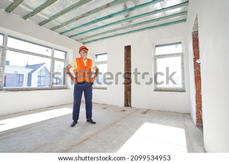 Builder inspecting empty room in unfinished building