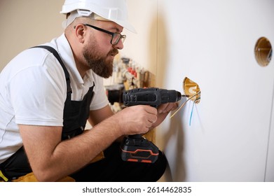 Constructor instalando toma eléctrica en apartamento nuevo. Instalación de tomas de corriente eléctricas con un destornillador en un nuevo hogar. Electricista que repara el zócalo de poder, cableado del montaje del electricista para los zócalos