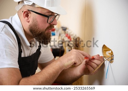 Builder installing electric socket in new apartment. Installing electrical wall outlets with a screwdriver in a new home. Electrician repairing power socket, electrician mounting wiring for sockets