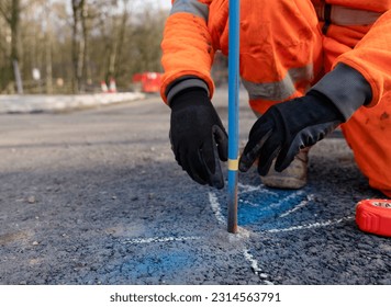 Builder marking future finish road levels on a road setting out steel pins with yellow electric tape on a road improvement project - Shutterstock ID 2314563791
