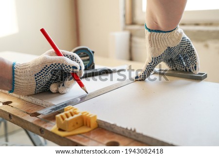 Builder measures and marks drywall sheet
