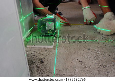 the builder measures the repair lines using a green laser level,