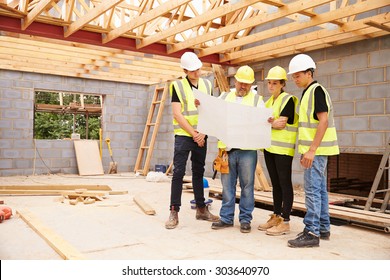 Builder On Building Site Looking At Plans With Apprentices - Powered by Shutterstock