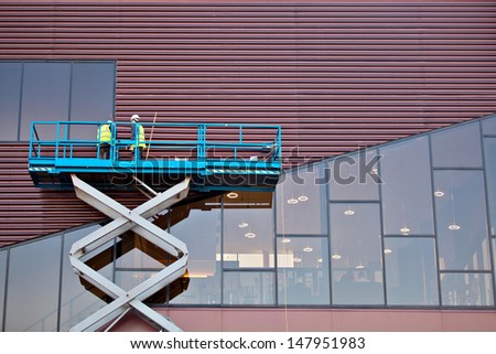 Builder on a Scissor Lift Platform at a construction site. Men at work