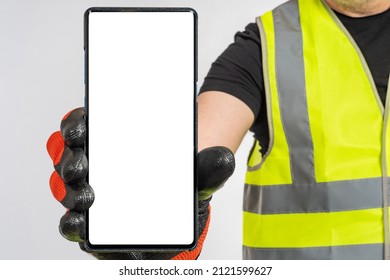 Builder with phone. Big hand shows smartphone. Blank phone screen close-up. Place for text on display. Copy space on empty phone. Cellphone for apps. Man in yellow construction vest in background