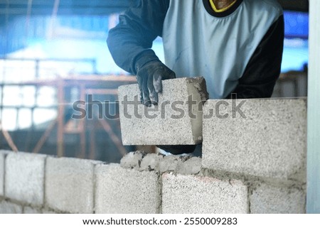 The builder places the block during the construction of the wall                                   