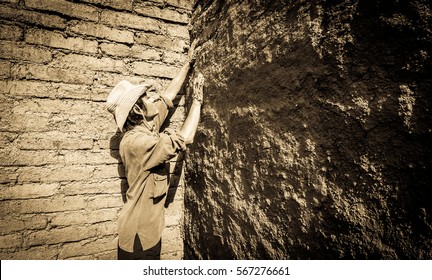 Builder plastering wall in earthen house.
