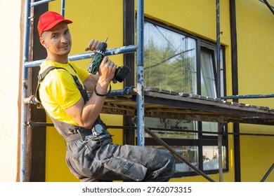 Builder in red cap with screwdriver on scaffolding, house facade, home repair, instrument kit, handyman visiting for at-home craft, maintenance and improvement.
