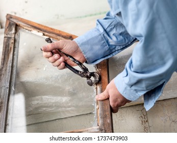 Builder Repairs An Old Wooden Window With A Pair Of Nail Puller Pliers. 