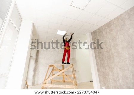 a builder replacing ceiling panel, working, armstrong.