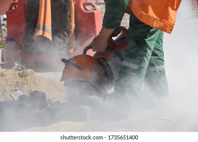 Builder Sawing The Curb With A Circular Saw, A Lot Of Concrete Dust, Highway Construction.