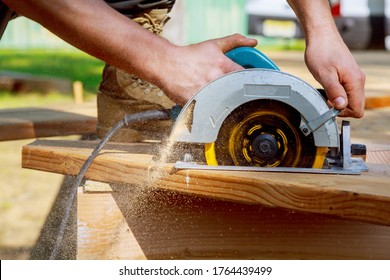Builder saws a board with a circular saw in the cutting a wooden plank - Shutterstock ID 1764439499