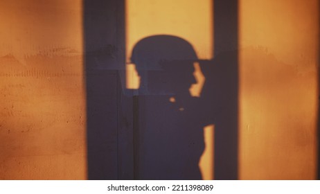 Builder Shadow Falls On The Wall Silhouette. Business Building Concept. Worker In A Helmet Silhouette Shadow Falls On The Wall With Plaster Idea Concept. Contractor In A Helmet Makes Home Repairs